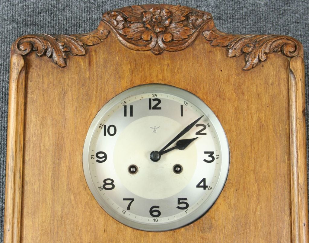 A German Regulator Wall Clock in Art Deco style dating to 1920 with a lovely oak case featuring stylized flowers and flourishes, an original leaded glass panel door, and marked with the stamp of Mauthe, recognized as one of the top clock producers