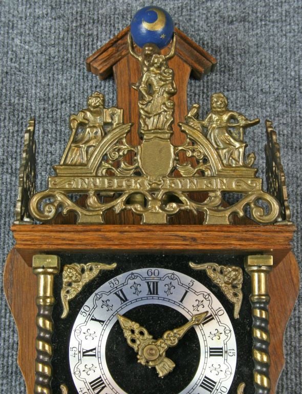 A vintage Zaandam Zaanse Style Pendulum Wall Clock from Holland dating to circa 1950 in oak and featuring the mythological figure of Atlas holding the world on his shoulders at the top.
