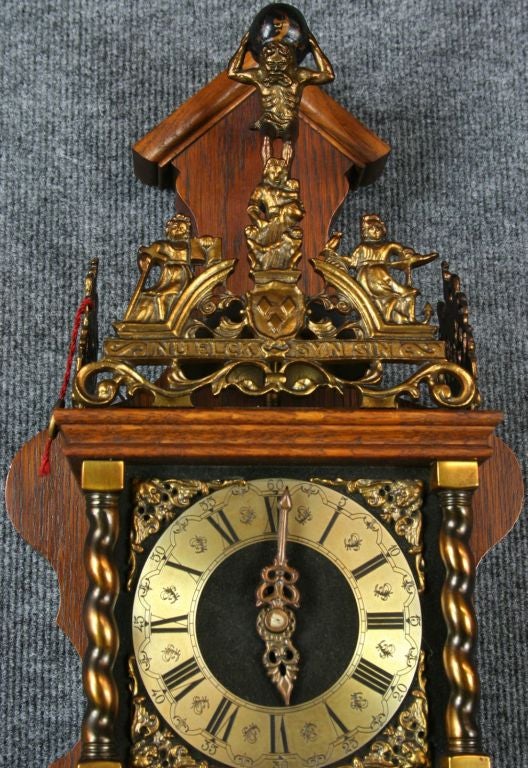 A vintage Zaandam Zaanse Style Pendulum Wall Clock from Holland dating to 1950 and featuring the mythological figure of Atlas holding the world on his shoulders. The clock is signed by the company Wuba and has the original Wuba tag.
