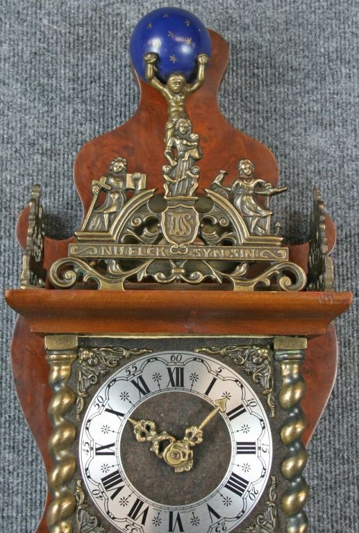 A vintage Zaandam Zaanse Style Pendulum Wall Clock from Holland dating to 1950 and featuring the mythological figure of Atlas holding the world on his shoulders at the top.