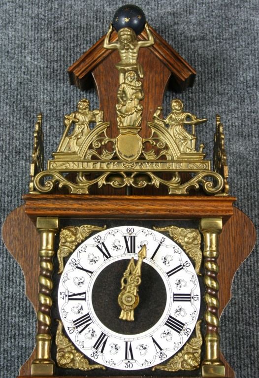 A vintage Zaandam Zaanse Style Pendulum Wall Clock from Holland dating to 1950 in oak and featuring the mythological figure of Atlas holding the world on his shoulders at the top.