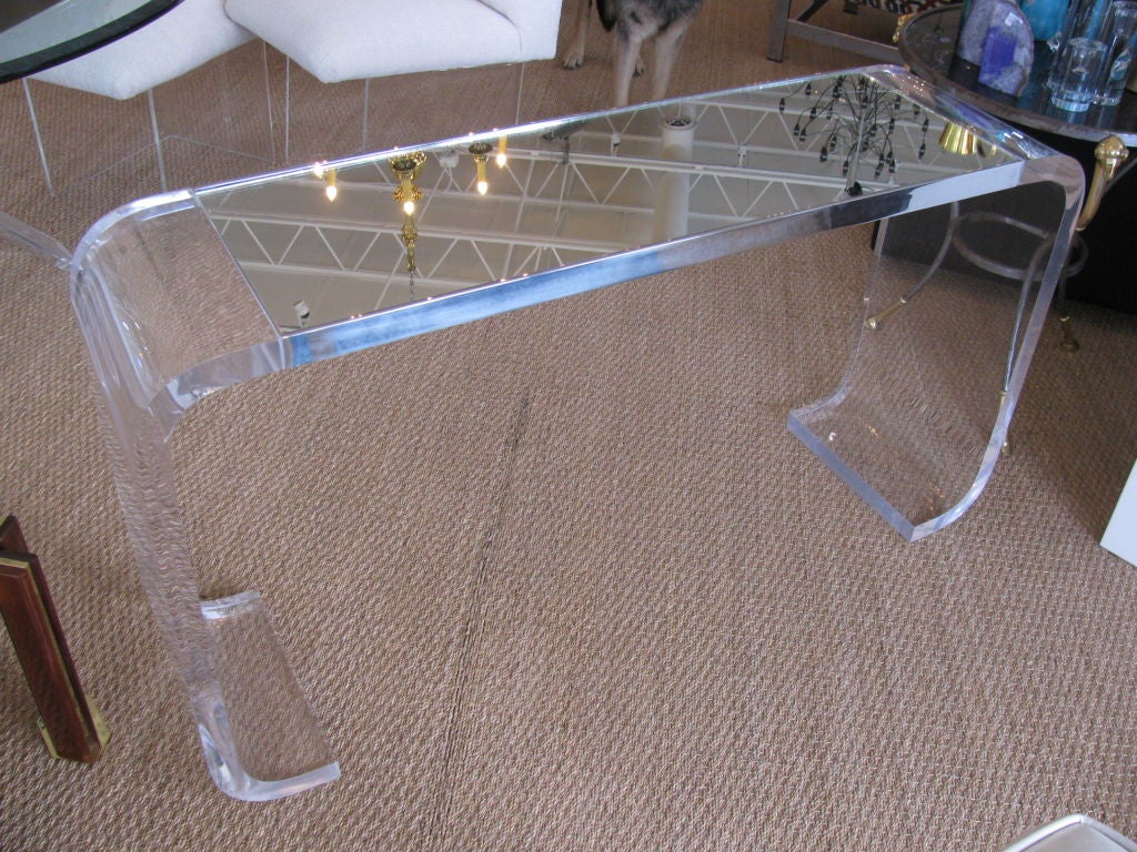 This elegant console is a unique detailed piece crafted from thick crystal clear lucite. The top is made of mirror and the piece can serve as a room divider or anything of the sort.