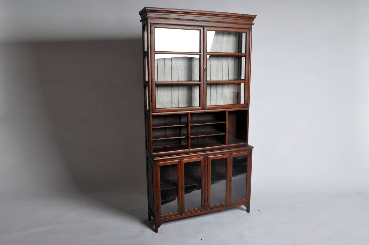 This beautiful British Colonial Display Cabinet is from Chiang Mai, Thailand and made from Teak Wood. Given its design it is probable that it was used as a mercantile piece or in a Colonial office for books and ledgers. Note the painted panels.