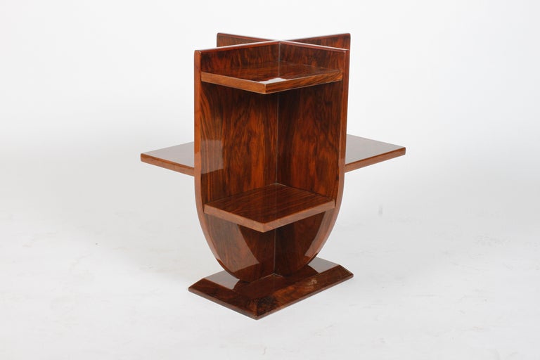 This elegant side table has alternating shelves on both sides.  Due to its asymmetrical design, it  has a unique appearance from every angle. The tulip shape is set upon a square base. The walnut veneer has been repolished to perfect condition,