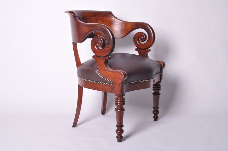 A distinctive, curvaceous round-backed chair with impressive weight and proportion. The rugged brown leather upholstery compliments the rich glow of the Acajou Wood frame.  This piece has been meticulously restored, with a new seat, retied springs