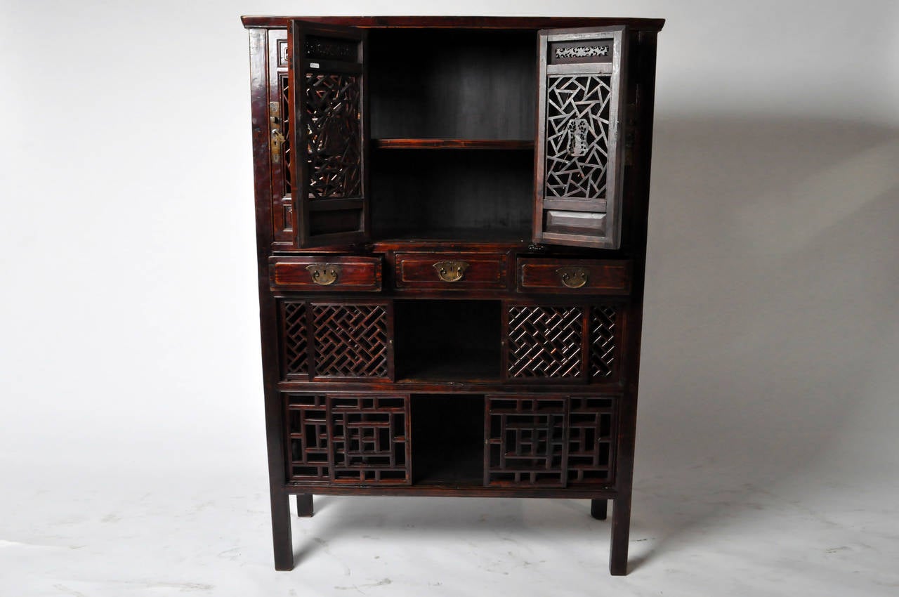 This charming Chinese kitchen cabinet has a playful assortment of doors, drawers, and sliding panels. It features multiple lattice motifs creating visual excitement and energy. This piece has been meticulously restored keeping most original parts