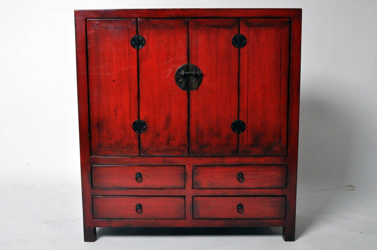 This red lacquered Chinese side cabinet is from the Zhejiang province of China and made from Elm Wood. It features 4 drawers, traditional mortise and tenon joinery, and bi-fold doors. It has been professionally restored.