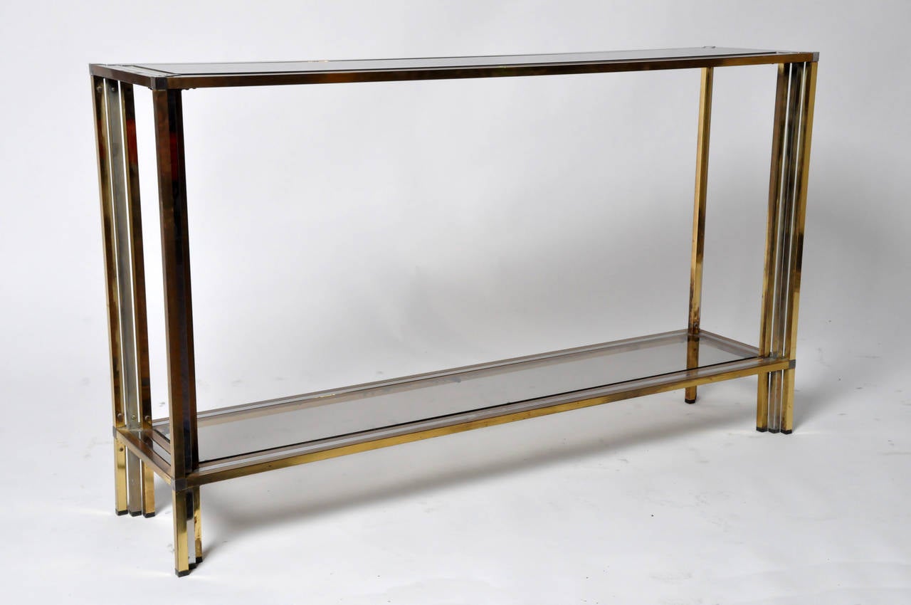 This stylish console table is from Paris, France and made from brass, chrome and glass elements. The piece features a smoked glass top and bottom shelf.