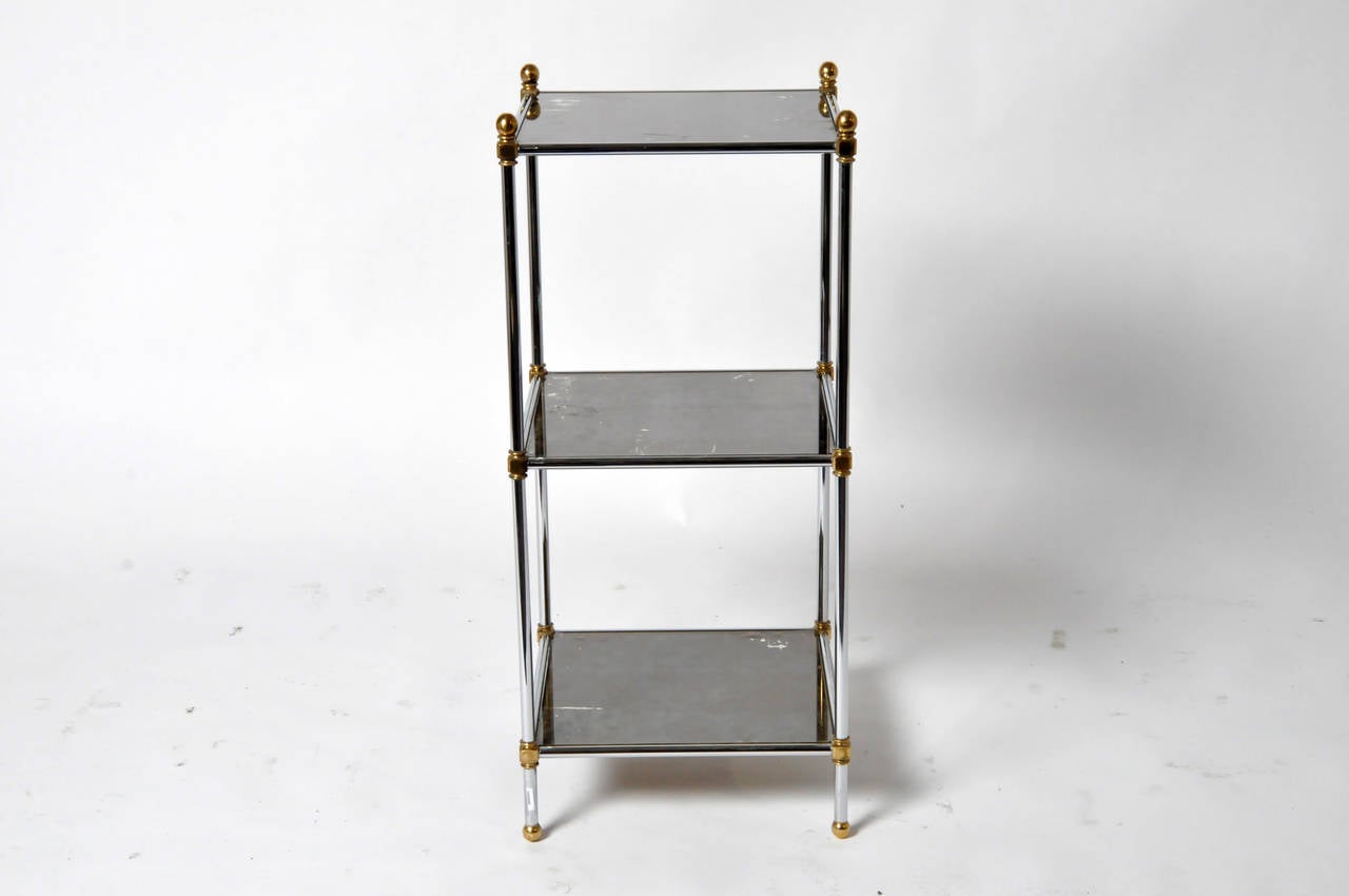 This gorgeous pair of side tables is from Paris, France and made from chrome and glass with bright brass decoration. Each table features three smoked glass and shelves. Glass is original.