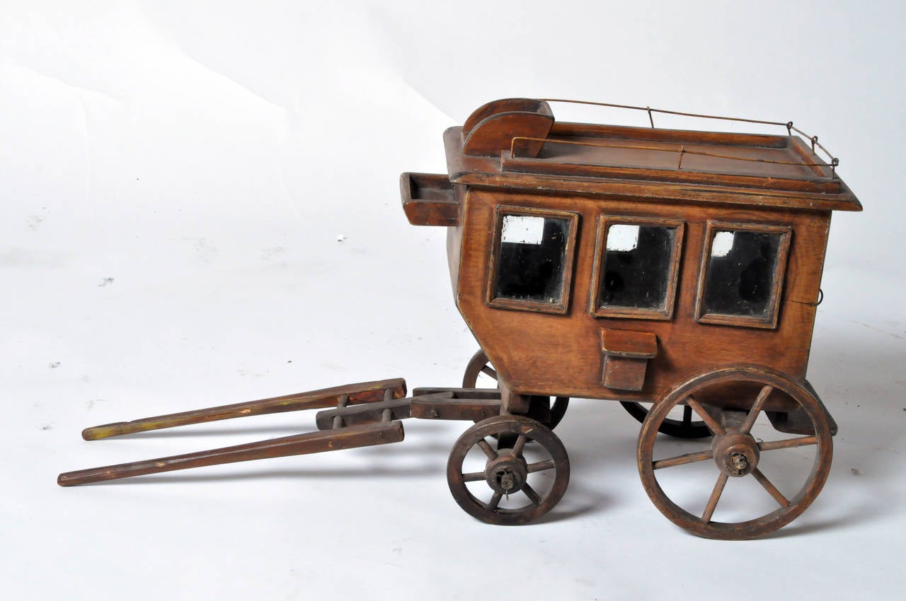 This wooden carriage toy is from France and made from wood and glass c. 1940. The doors and wheels are functional.
