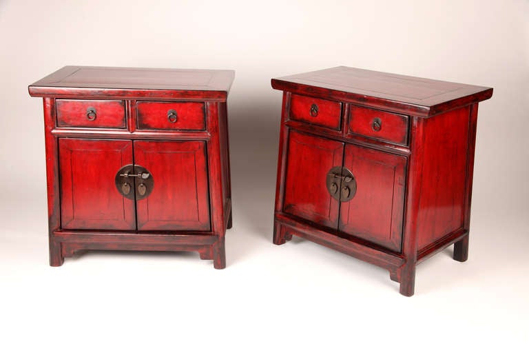 This pair of 19th century tapered bedside chest has two drawers, storage, and round post legs. They are made from elm wood with red lacquer and has some restoration done.