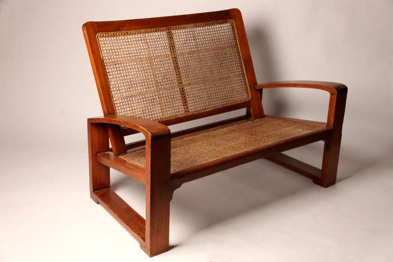 This bold and angular Art Deco settee has a study Teak frame and new rattan seat (new). It was made for use on the veranda.  This piece is Burmese, probably from Rangoon.