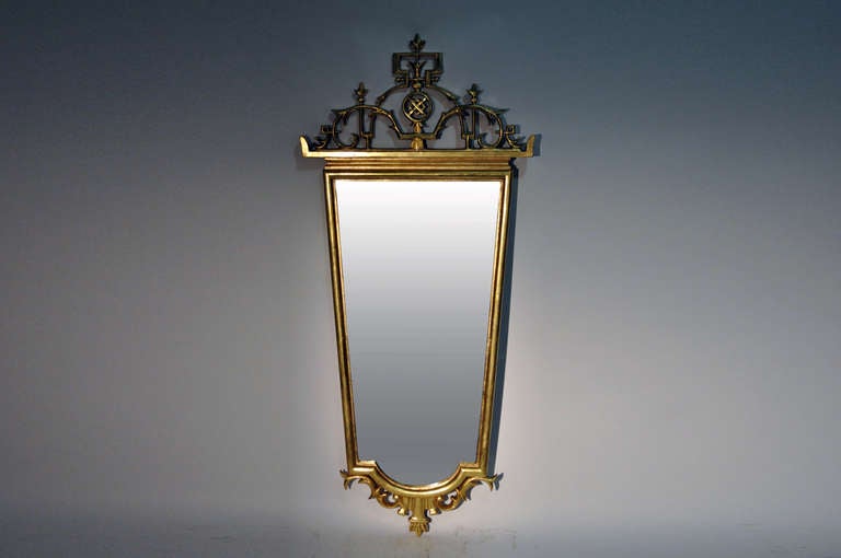 A stunning blend of styles play beautifully across this mirror; the clean lines of the tapered mirror plate are elegantly framed by chinoiserie-style motifs including scrolling foliate, geometric shapes and floral-form finials.