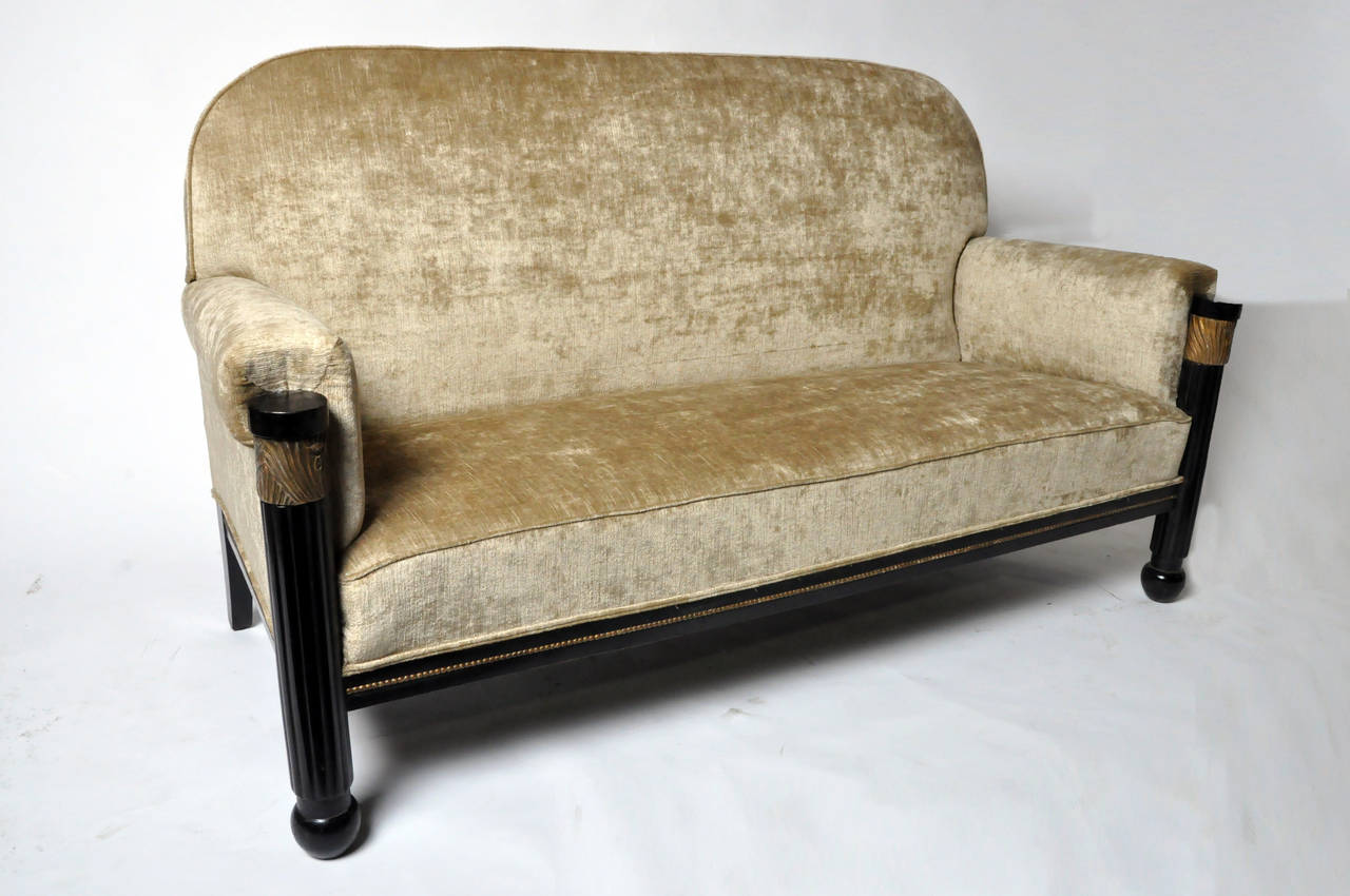 This comfortable sofa features a pair of fluted column-form front legs that terminate in ball feet. There is more than meets the eye, the exquisite brass-like detailing on the legs and frame is well-disguised giltwood inlay in the form of floral