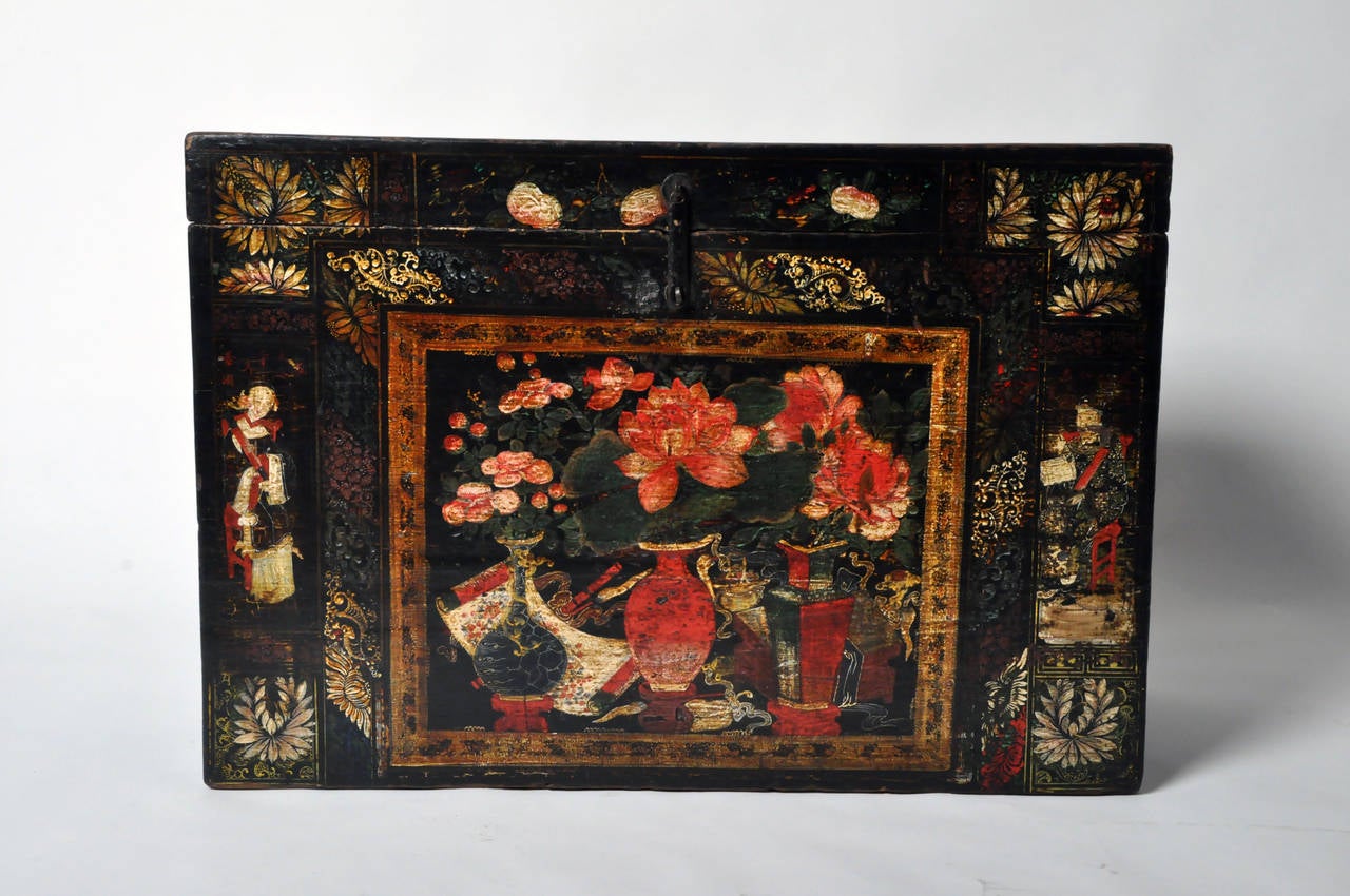 Made of lacquered Elm Wood, this trunk was used to store household items and clothing. The front of the chest is hand painted with budding floral arrangements in three Chinese baluster vases, encompassed by a gold floral motif border, surrounded by