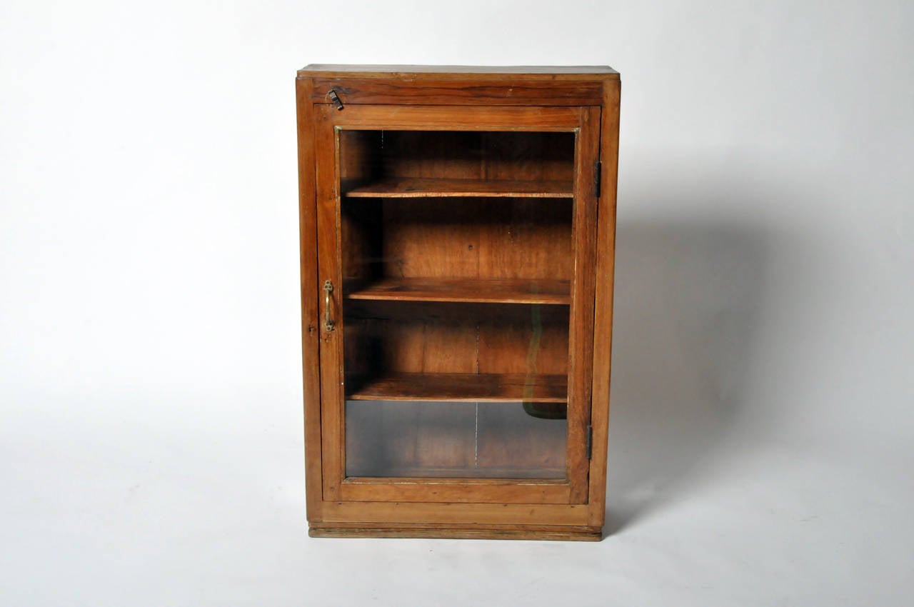 Comprising four shelves with glass front and sides. This piece was used in a Burmese dry goods shop until the 1980s.