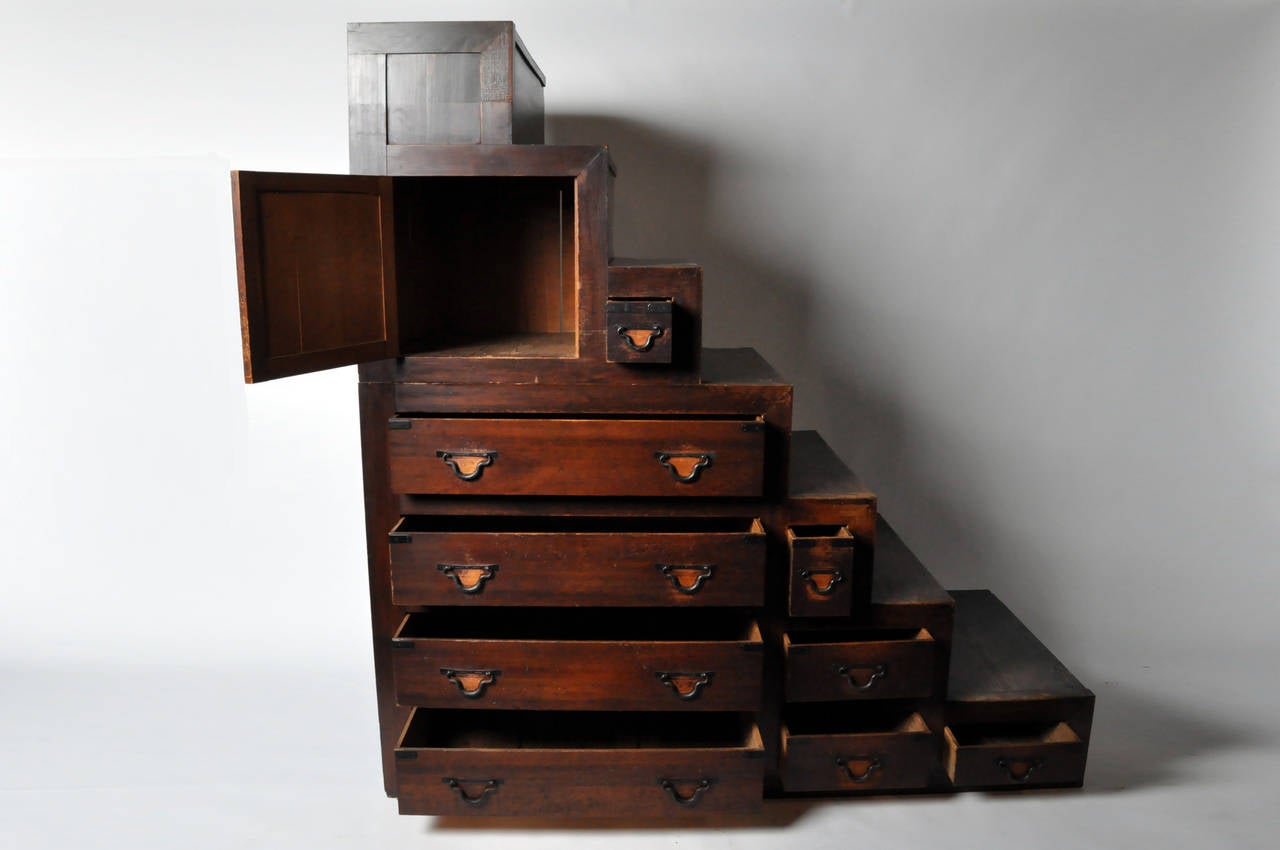 This monumental Kaidan Tansu is from Japan c. 1900. It features nine drawers of various sizes, and iron hardware. Made of wood from the Zelkova Serrata tree, which is closely related to the Elm wood family. This is a unique conversational piece.