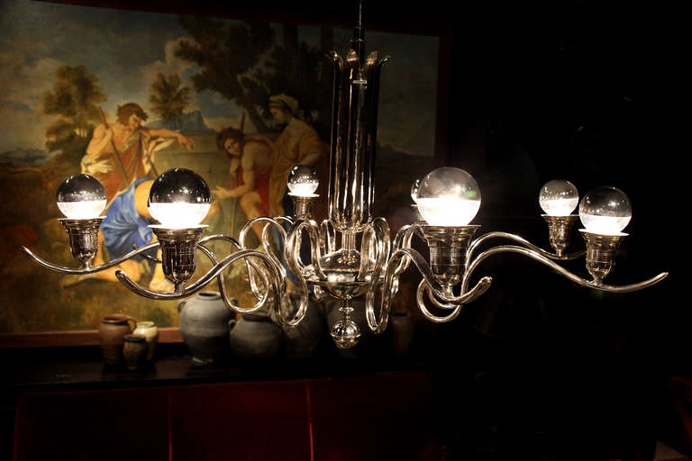 This graceful eight-light chandelier has fluid, ribbon like S-scroll arms that extend from a central column.
