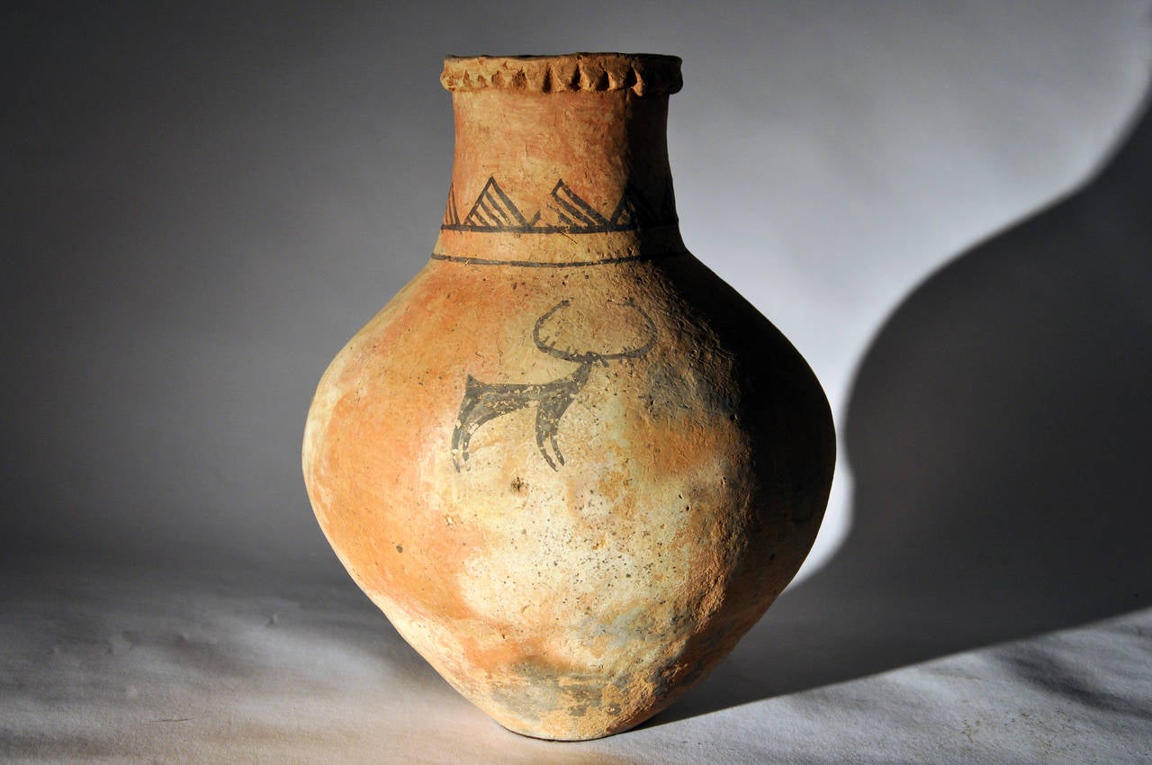 With remaining natural red pigments, this vessel is decorated with black geometric and linear designs, as well as depictions of deer. Lin-Chih region, Tibetan Plateau. K'a-no culture.
