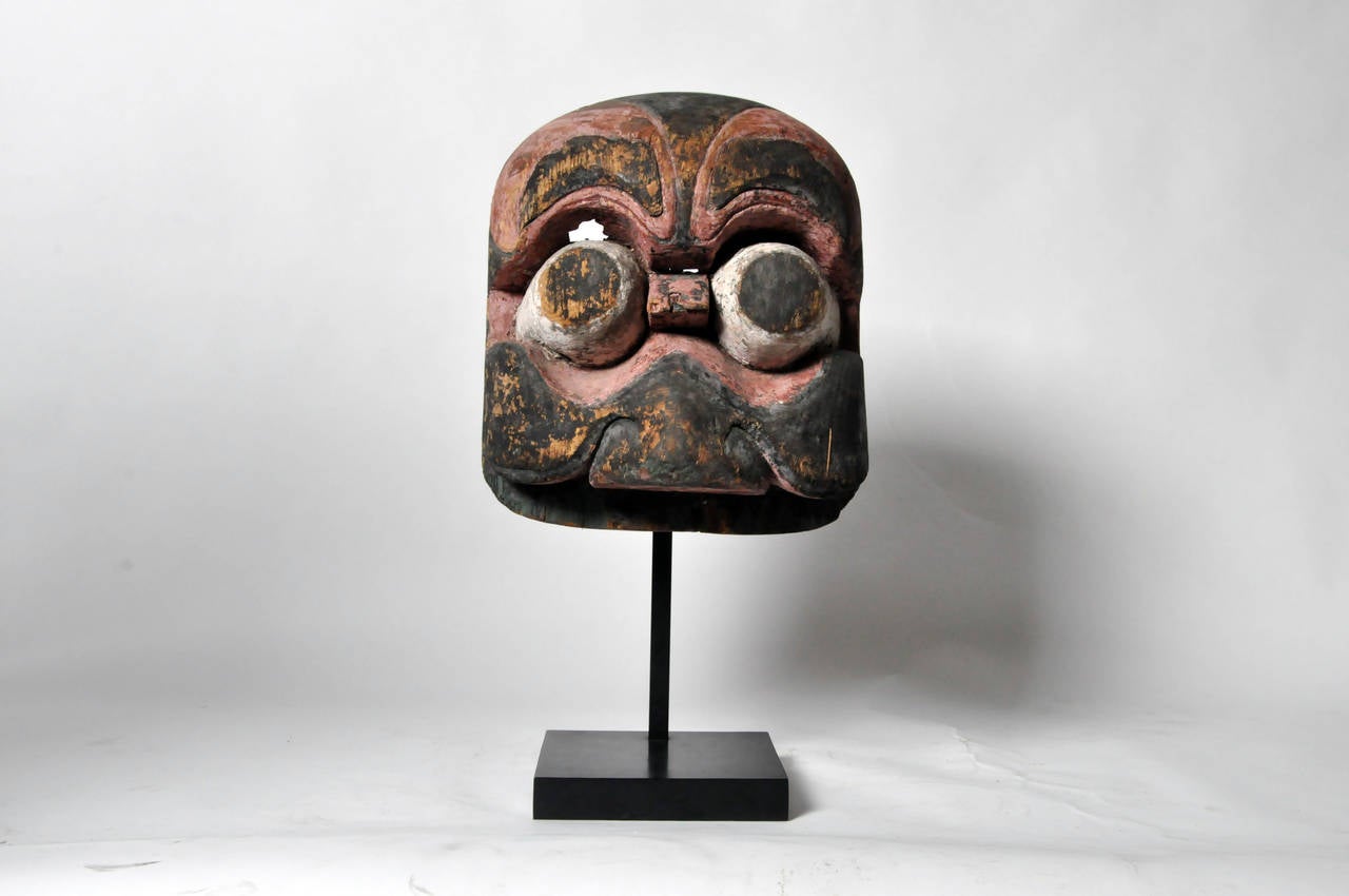 This highly stylized 19th Century mask is from China and was used during New Year's celebrations. Carved from Elm Wood, the piece retains much of it original bright pigment. The piece was designed to ward off evil spirits.