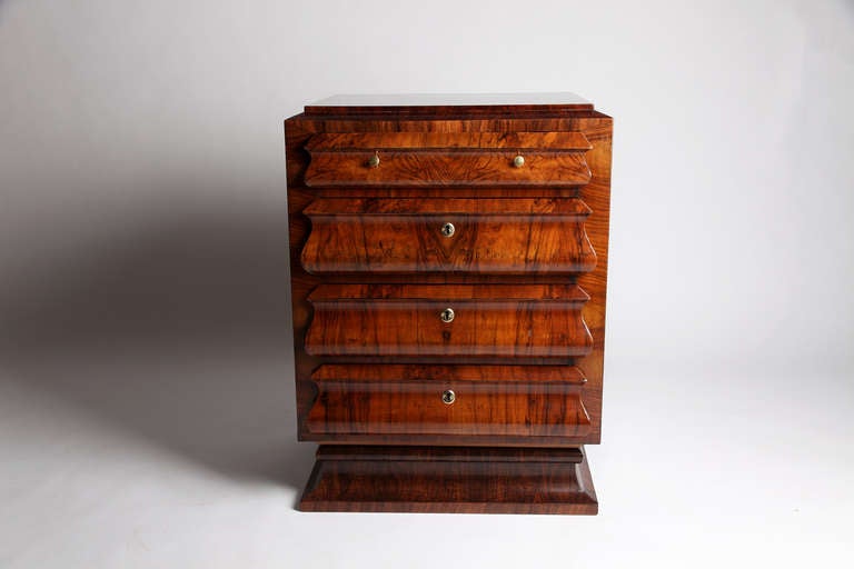 This side chest combines sharps angles and soft curves to create a distinctive look. It features four drawers, three of which lock, raised on a pedestal base. The lustrous original Walnut Veneer was given a fresh coat of polish.