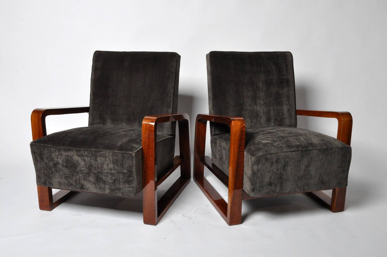 This handsome pair perfectly balances a combination of contrasting elements: Dark velvet-like upholstery and thick padded seats framed by thin, high-gloss streamlined arms with sleek rounded edges. The open arms lighten their otherwise substantial