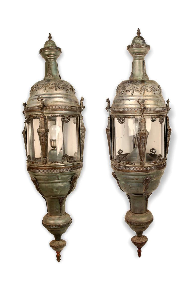 These stunning French sconces feature neoclassical style ornamentation including: flame-form finials, applied swag and ribbon decoration, Putti or cherub figures on tapering stylized pedestals, classical female masks and scrolling foliate and shell