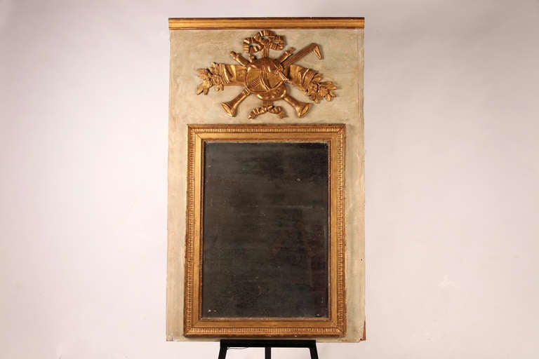 Above the framed mirror plate, the panel is decorated with a floral motif and carved musical instruments.