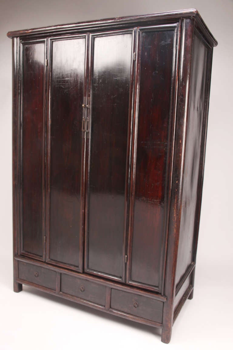 This elegant 19th Century storage cabinet is made from dark red lacquer over Elm Wood. It is an excellent example of Ming-Inspired scholar's furniture with a round posted frame and without any unnecessary decoration. The piece is very voluminous and