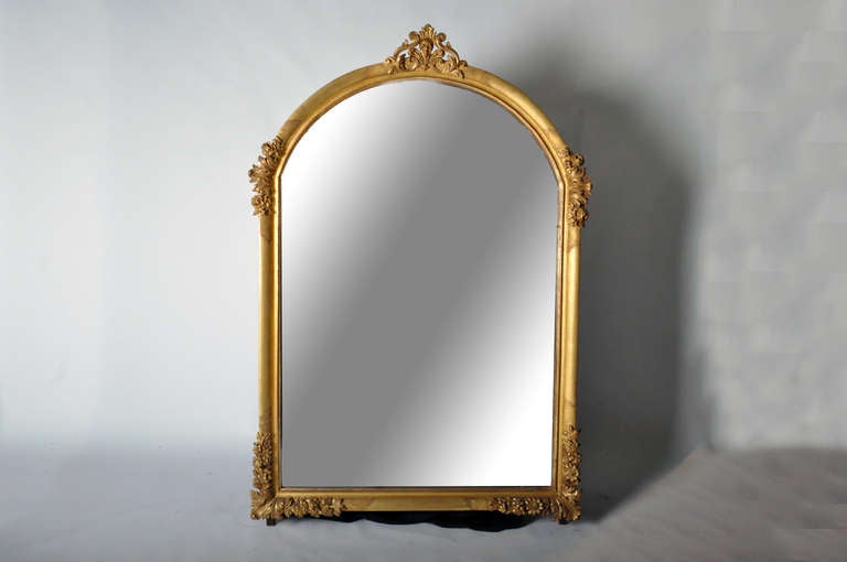 This elegant 19th century carved gold gilt mirror is from France and is made from beechwood. Due to its large size the mirror glass is in two parts. All carved are actual wood, not plaster. Glass is old but not original to the mirror.