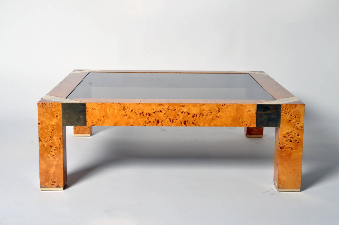 This low table has beautiful contrast between the light burl wood veneer, the brass corner ribbons and the original dark smoke-grey glass top.