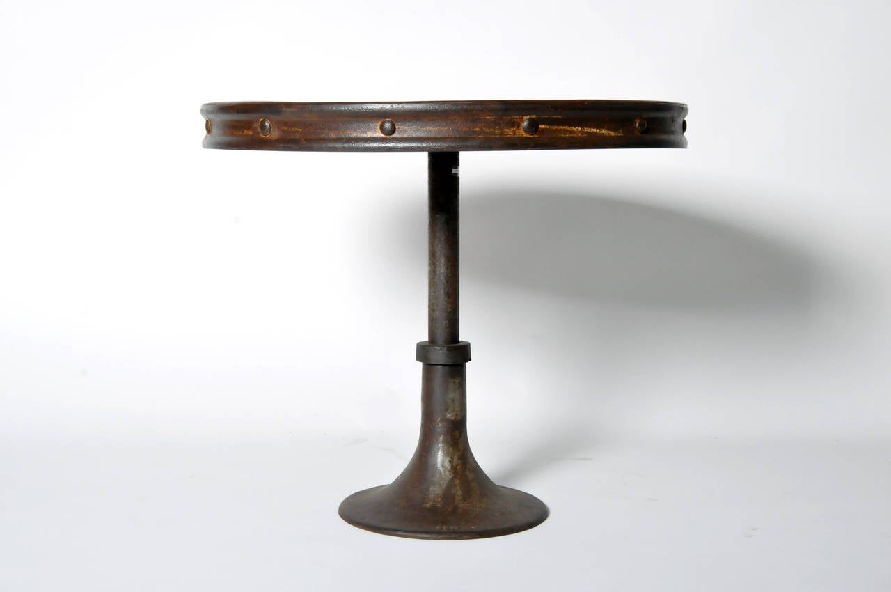 The rough oxidized iron and steel surface contrasts with the table's elegant roundness. Originally an Industrial piece, the table is ideal for casual dining use.