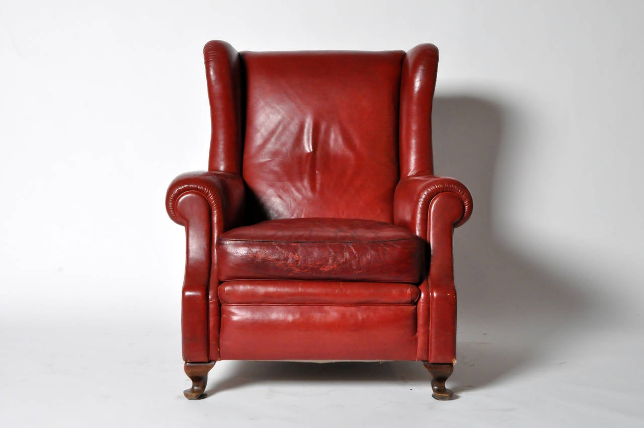 This Classic red leather wingback chair is raised on squat cabriole legs, which terminate in rounded feet. A row of tightly-placed brass studs adds interest to the chair's back and sides.