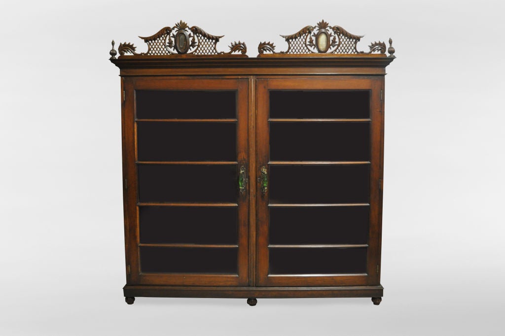 This large and impressive British Colonial bookcase is from Rangoon, Burma, made from teak wood and dates to the early 1900's. The piece retains its original varnish which has yellowed with time. The carved decoration is unusually fine for a