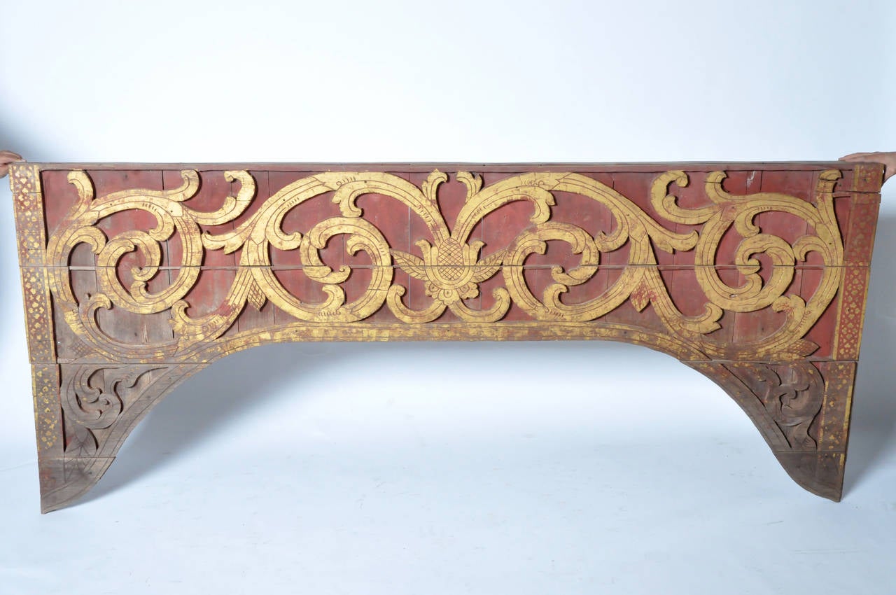 This hand-carved fragment has a raised floral motif decoration over a red painted background. An additional geometric patterned border flanks each side.