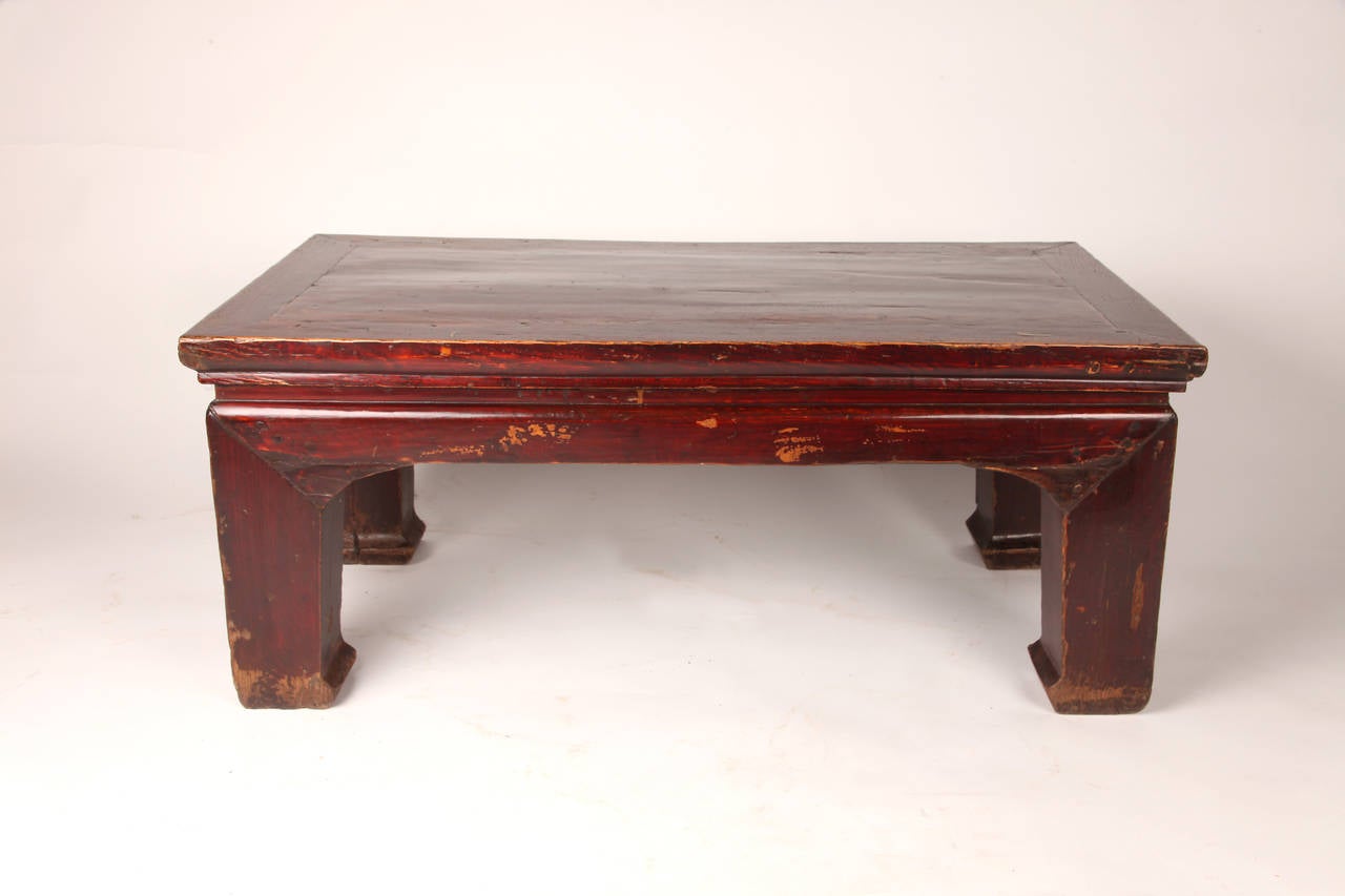 Chinese elmwood tea table of typical waisted form, having thick corner legs that terminate in horse-hoof feet.