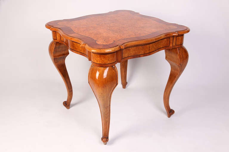 Having a square top with parquetry inlay, raised on cabriole legs terminating in scroll feet.