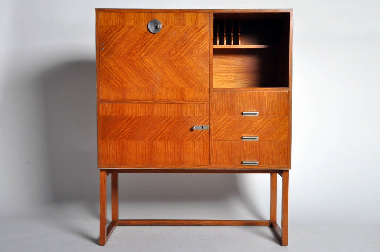 Straddling the line between late Modern and early Mid-Century Modern design, this secretary desk is compact in size. The drop-front opens into a writing table with shelves and two drawers. Ample storage space is available in the lower compartment as