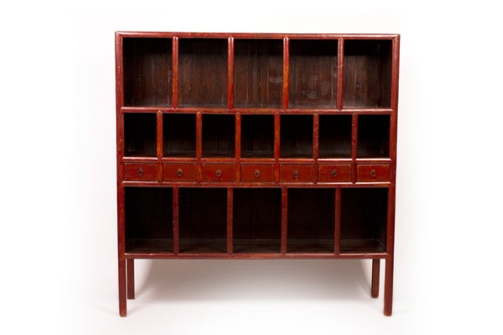 This handsome red lacquer bookcase comes in two parts. The central cabinet (main image) boasts versatile storage space in the form of three open shelves and seven drawers, each with metal ring pulls. A framed shelf extension can be added to the top