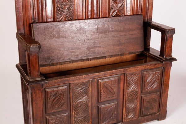 This heavy Oak bench with high back and decorative cornice was once used as pew on a raised sanctuary in a church. It now functions perfectly as an entry piece with hidden storage under the seat to sit down, take off your shoes and store thema