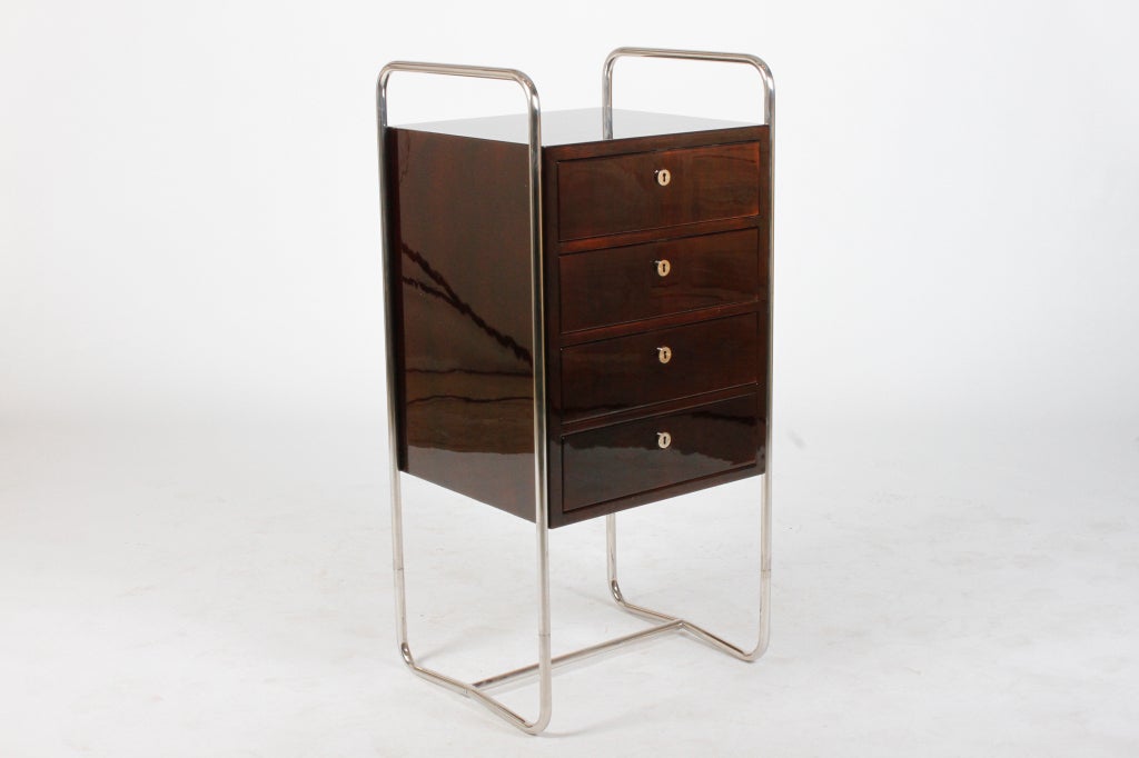 A tubular chrome frame holds four drawers with functioning locks and keys. Made from handsome high-gloss Black Walnut veneer this sleek piece is a striking, yet subtle presence in any room.