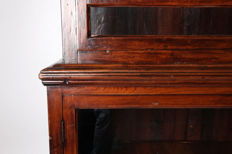 This teak bookcase is one of the sturdy and handsome British Colonial furniture that was made in Burma during the British Raj.   

This bookcase was probably used in a colonial office.      Its teakwood frame, along with the glass & wood doors once