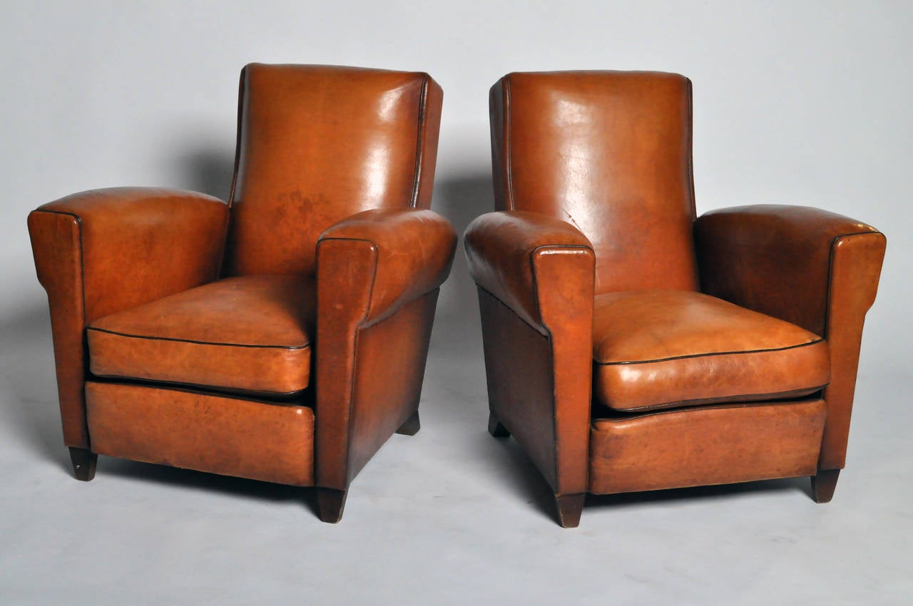 These vintage club chairs are more angular and upright than most French club chairs. They are also exceptionally comfortable, due to their soft lamb leather surfaces.