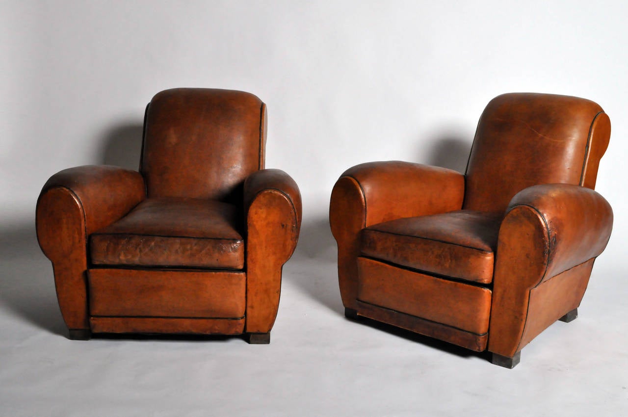 This stylish pair of leather club chairs has been carefully reconditioned, preserving the beautiful original patina. Leather is sheep leather.