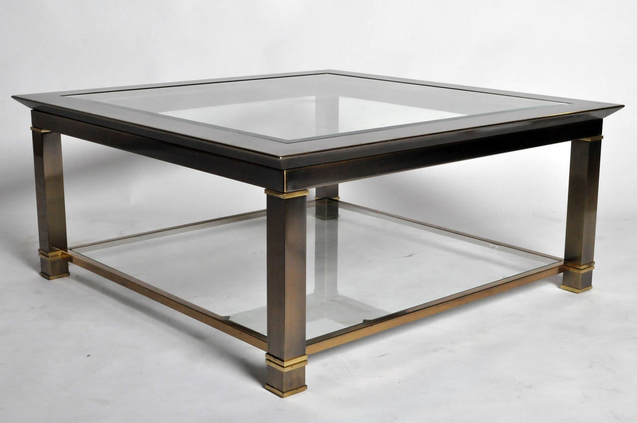 This impressive square table features a bronze-toned brass frame with bright brass details. The lower shelf is sturdy and practical for the display of art books and artifacts.