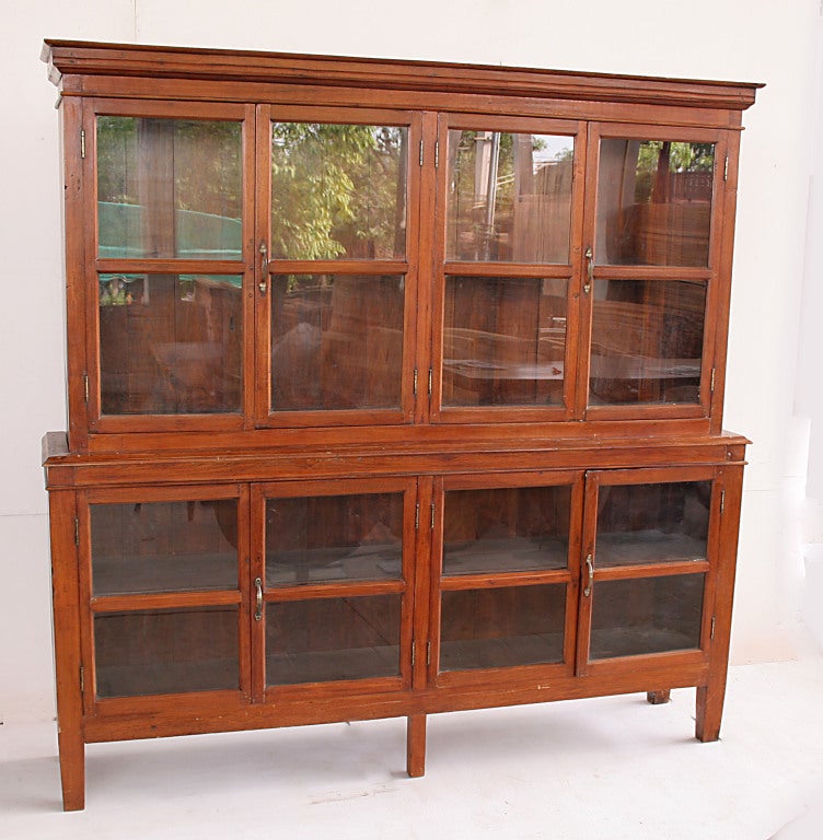 This substantial Raj bookcase was made from Teak wood by native Burmese craftsman in the British style.  Teak bookcases protected books and ledgers from tropical insects and dust; insects dislike the scent of Teak. This piece comes in two parts for