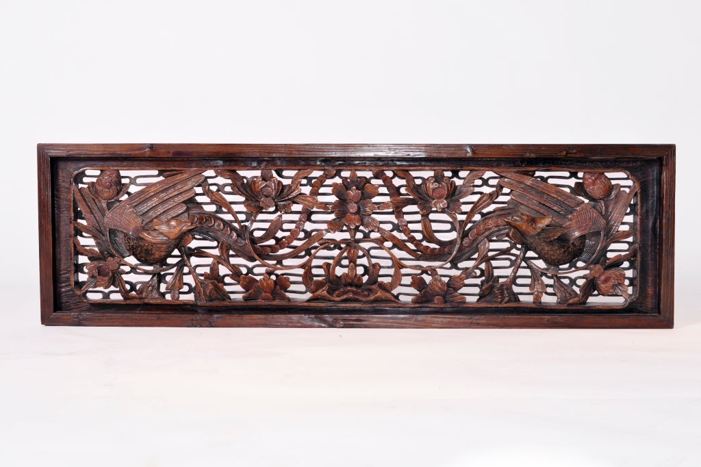 This detailed panel is made from Camphor wood and is intricately pierce carved with multiple layers of decoration. A pair of phoenixes surrounded by twisting vines and blossoms flank a central lotus flower, which is the Chinese symbol of