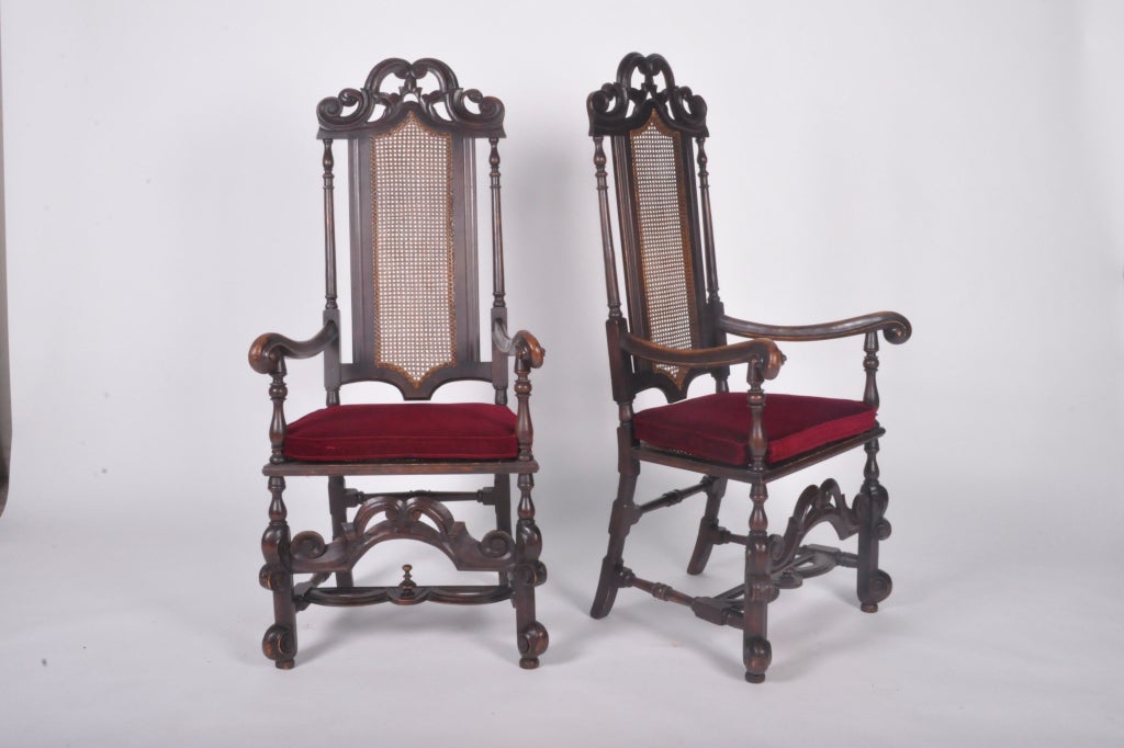 Having scroll-form crest rails, arms, and legs, with canned backs and padded seats. A decorative scroll work stretcher sits above an H-form stretcher with a round tiered finial.
