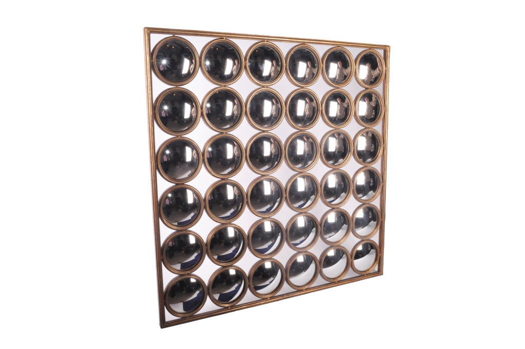 Curved mirrors from France that were used at hotels in France for security purposes are now aligned together in a panel now used as beautiful wall decorations.