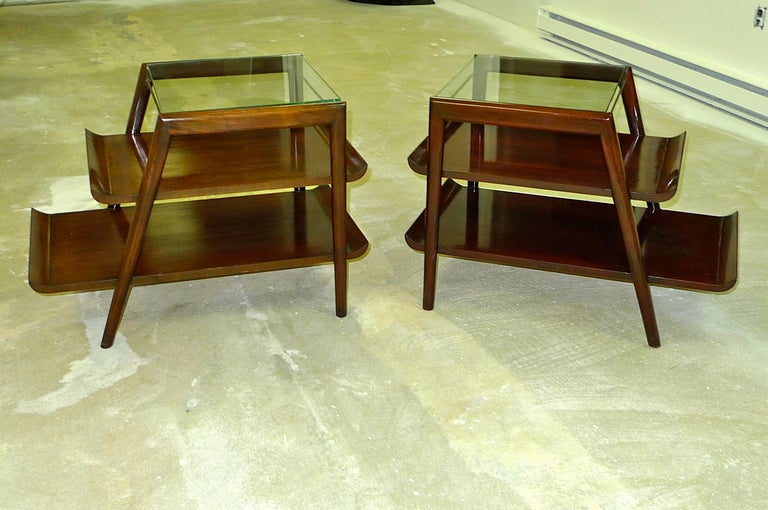 Pair of 1950's three tier step-end tables with glass insert top shelf on brass rod stretchers and a dark mahogany finish.  Middle and bottom tier shelves have winged edges in the manner of similar designs by Gio Ponti and Bertha Schaefer for M.